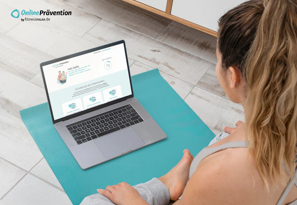 Sportlich gekleidete Frau sitzt auf dem Boden, vor sich einen Rechner mit dem Online-Krafttraining-Programm